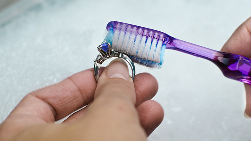 sapphire jewelry in a cleaning bowl and a toothbrush