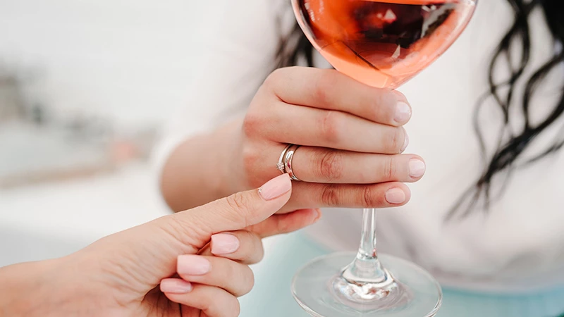 girl wearing cocktail ring holding a glass of wine